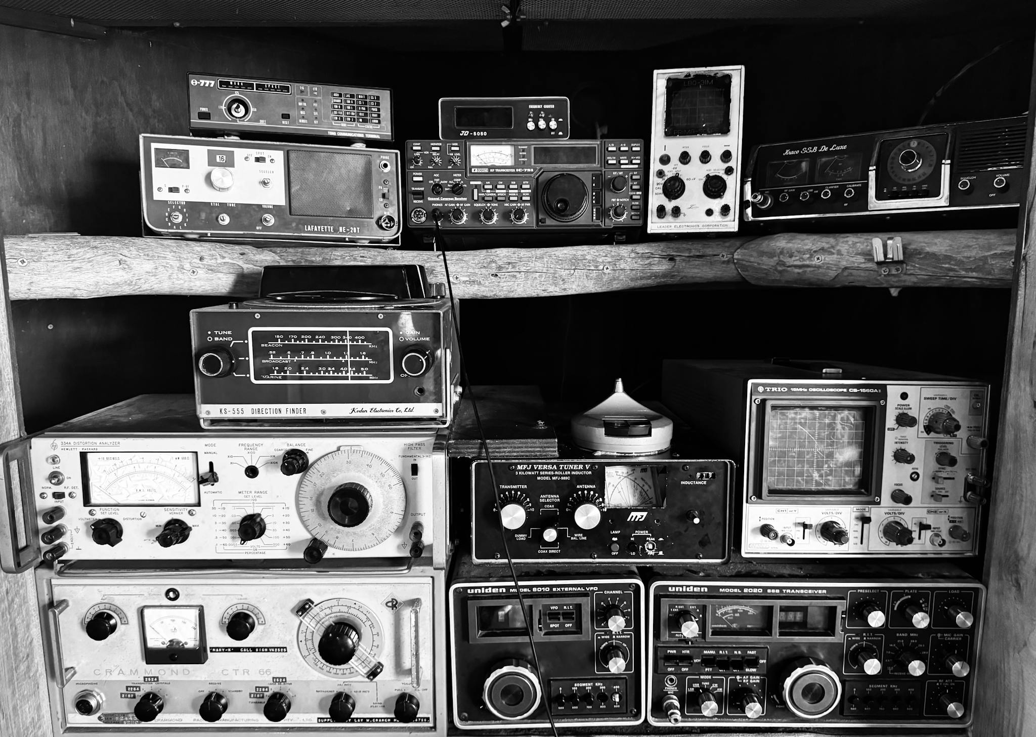 A black and white display of vintage radio devices on a rustic wooden shelf in Werribee, Australia.